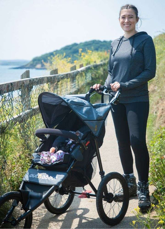 Woman wearing FittaMamma maternity activewear leggings while pushing a stroller outdoors, showcasing postnatal versatility and style.