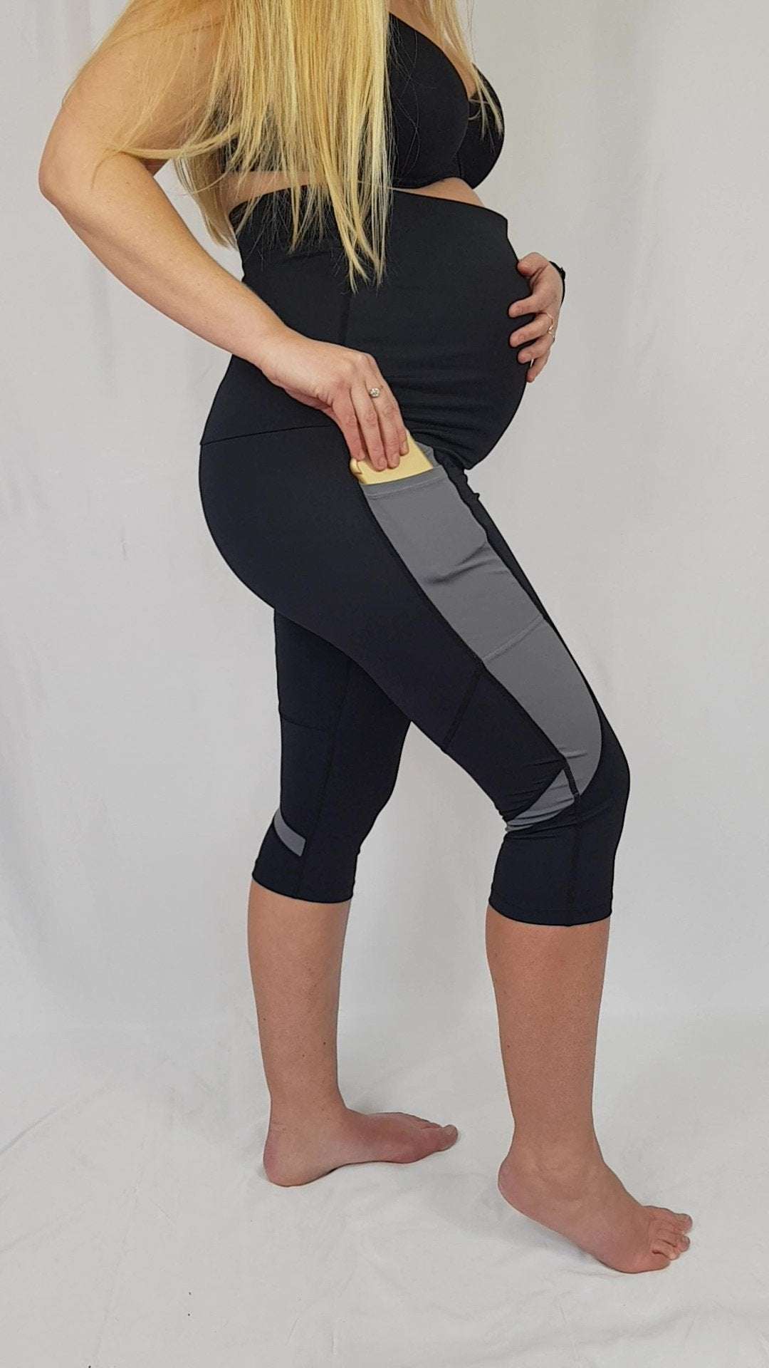 Side view of pregnant woman wearing Ultimate Maternity Workout Capri Leggings with phone pocket and high-support waistband for active moms.